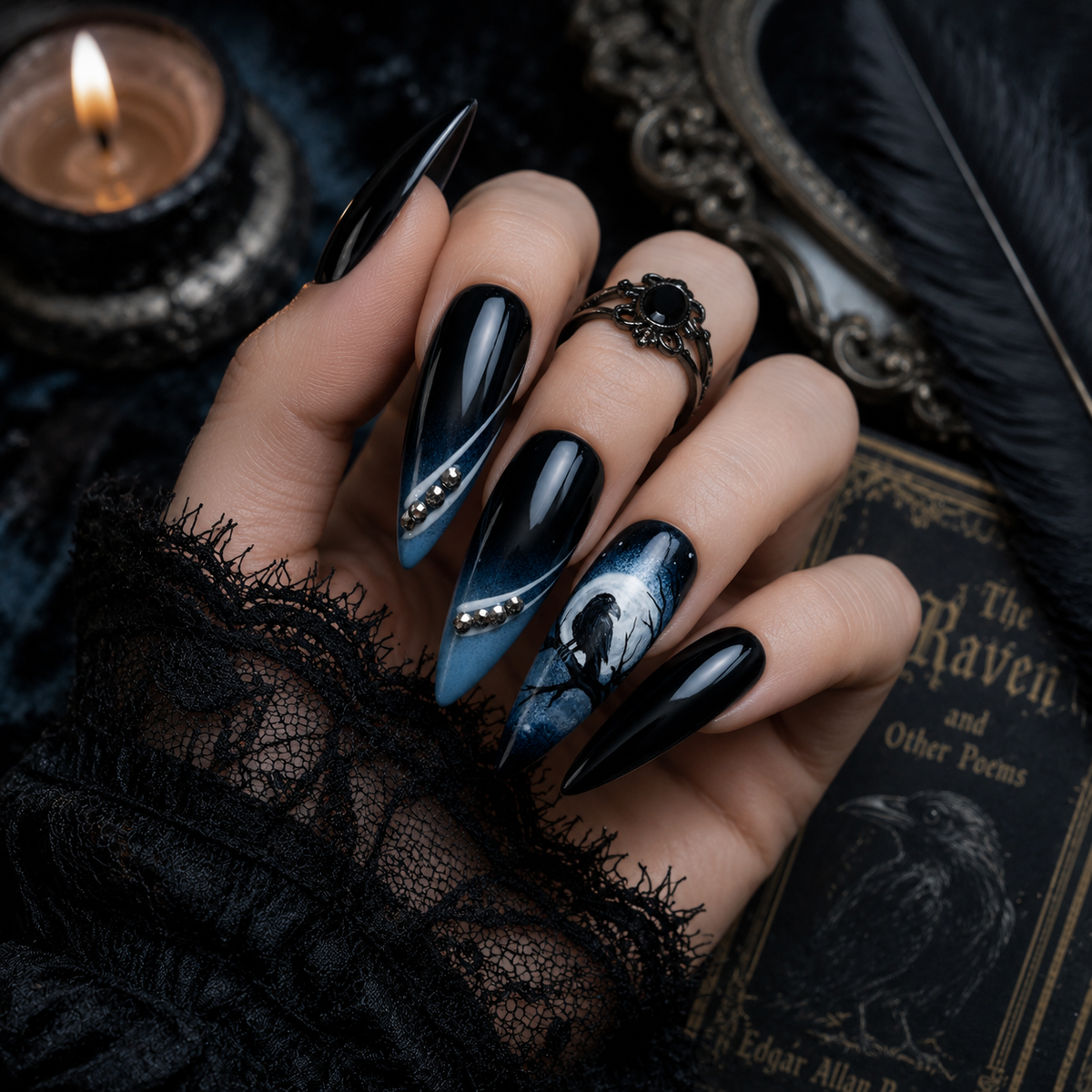 A hand wearing long black and blue House of Ravens stiletto nails with raven artwork.