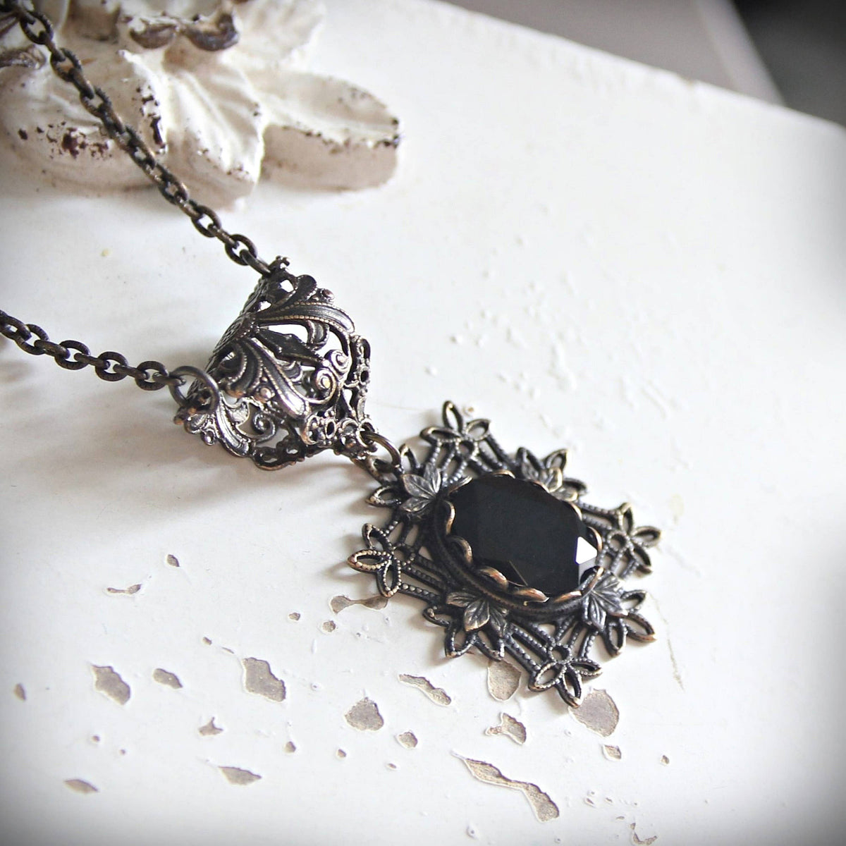 Antique-style silver filigree necklace with a faceted black gemstone pendant.
