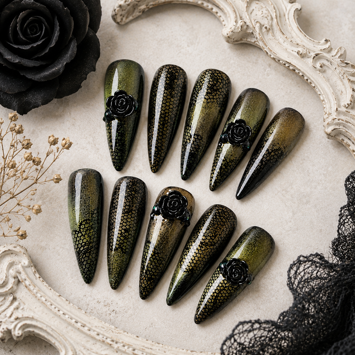 Black-and-gold stiletto press-on nails with lace detailing and sculpted black roses.