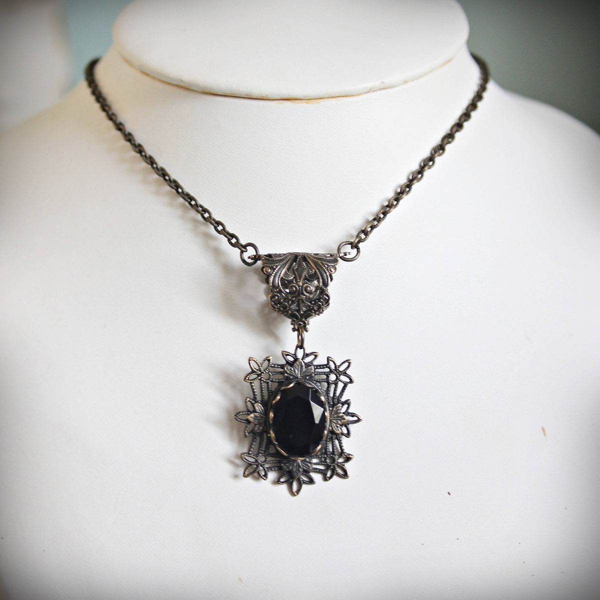 Antique-style silver filigree necklace with a faceted black gemstone pendant.